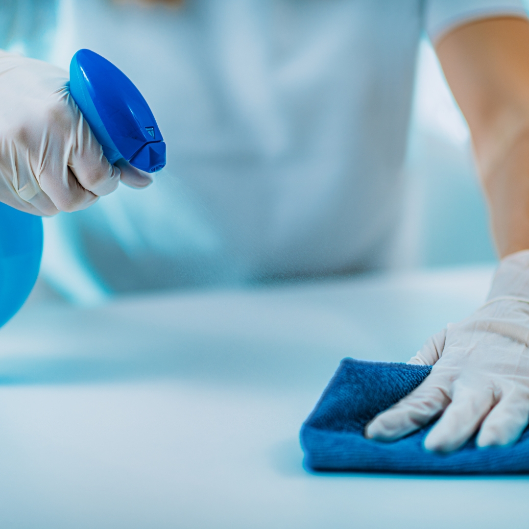 Mitarbeiter des Hygienelabors desinfiziert einen Tisch